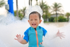 Portraits of happy little Asian baby boy smiling having fun in Foam Party at the pool outdoor.